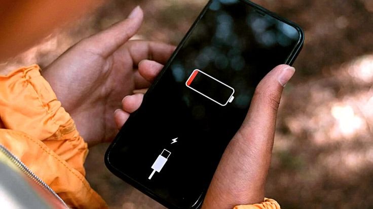 Pessoa segurando um iPhone descarregado, representando sinais de que a bateria do iPhone está no fim.